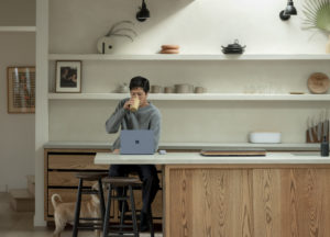 Hybrid employee working on portable device in kitchen.