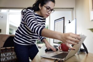 Female working remotely from her home office on an HP Elitebook device, standing at her desk.