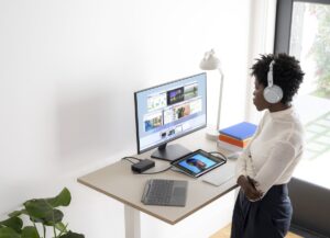 Contextual photography of adult female using Surface Pro 8 docked with Surface Headphones.