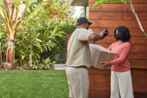 Delivery person hands package to customer.