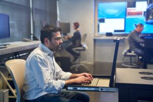 Man in a collared shirt working on a server station inside a secure room.