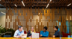 A group of tech workers hold meeting in common space of US office.