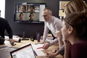 Small medium business employees collaborating using PowerPoint and Microsoft Teams; collaboration; conference room.