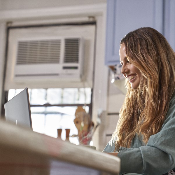 Woman working on laptop in kitchen.