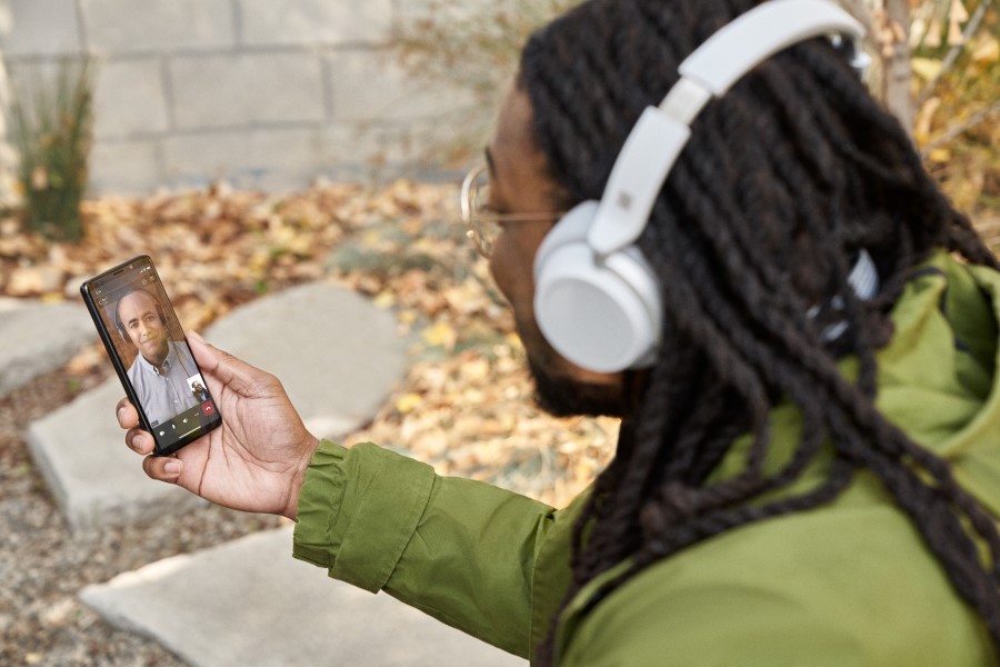 A man participating in a Microsoft Teams video call on his mobile phone while sitting outside​.