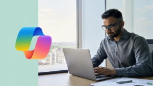 Executive sitting at desk using laptop in an office with a panoramic view. Including Copilot logo.