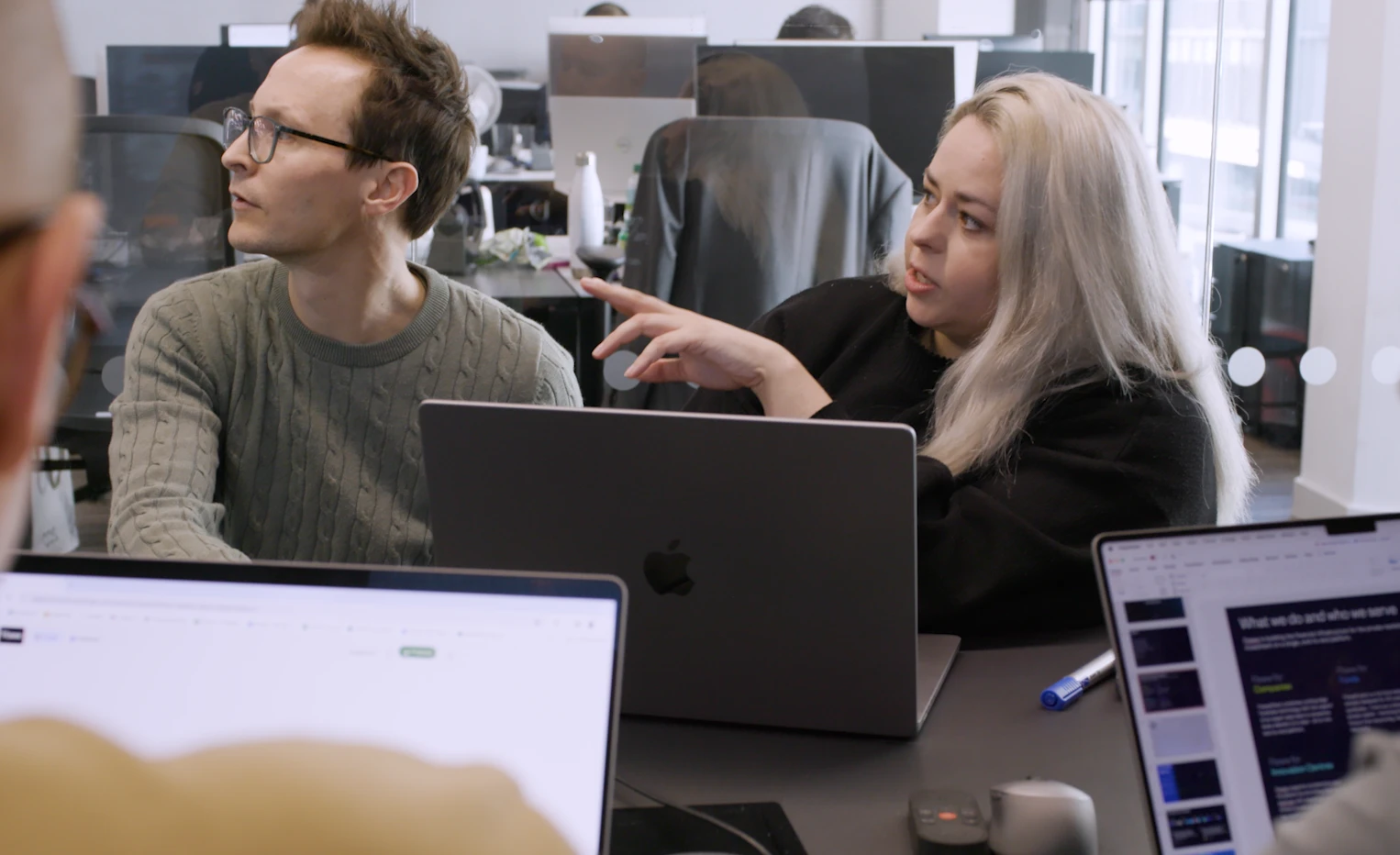 a group of people sitting at a table using a laptop computer