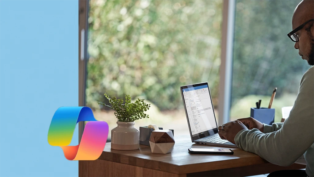 A person sitting at a table in front of a window using Microsoft Copilot.