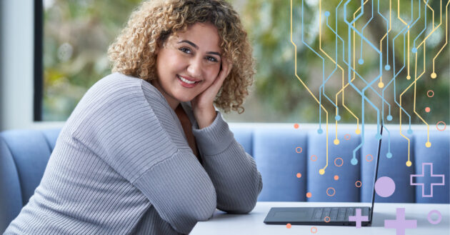 A woman sitting at a table with a computer open in front of her.