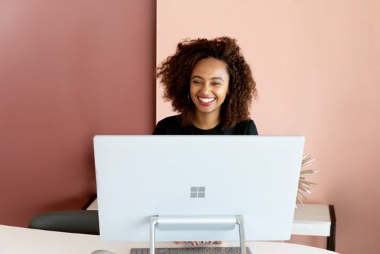 Smiling woman sitting behind a Microsoft-branded computer