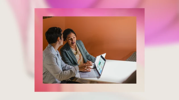 A picture of two business professionals working together on a computer over a decorative abstract blurred background