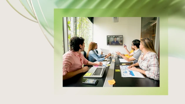 A team of coworkers sitting at a table and working on a project using AI