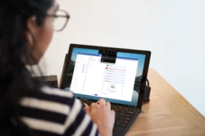 a person sitting at a table using a laptop computer