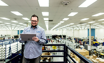 Image of a worker in a warehouse looking at a tablet.