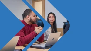 A man and woman talk together sitting in front of a laptop.