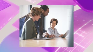 Three people look at a laptop screen together.