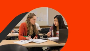 Two female students study together with open books and a device.