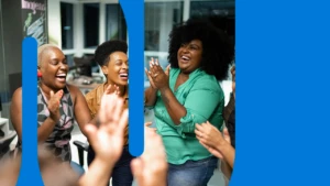 A group of women in an office gathered around clapping.