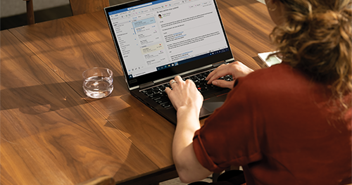 Over the shoulder photo at a dining room table with a Lenovo ThinkPad X1 Yoga.