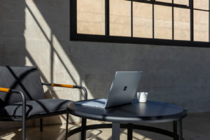 Commercial contextual lifestyle image of Surface Book 3 at desk in office alone.