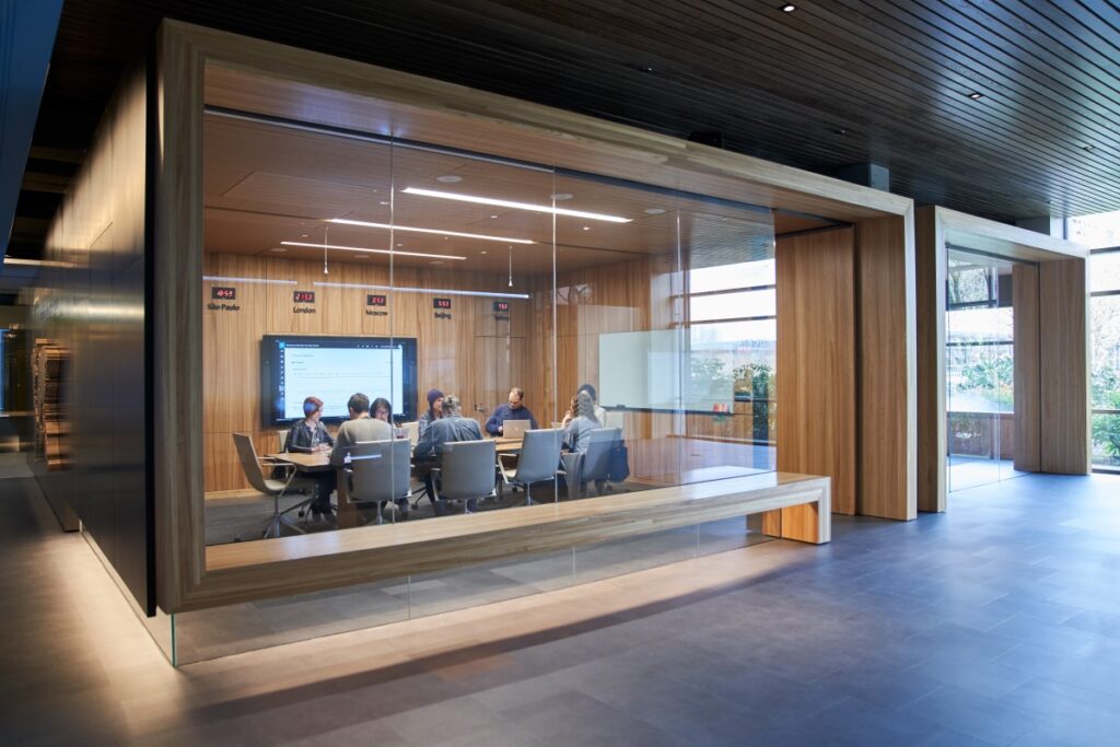 Outside of a conference room or board room meeting including people sitting around table in a room with international time clocks.