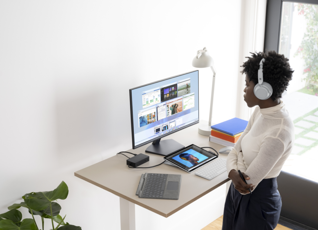 Contextual photography of adult female using Surface Pro 8 docked with Surface Headphones