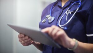 Female surgeon typing on digital tablet in hospital or surgery.