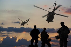 Three marines in the foreground with two helicopters in the background.