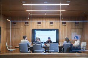 Looking into a conference room or board room meeting including people sitting around table in a room with international time clocks.