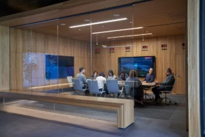 Conference room or board room meeting with people sitting around table in a room with international time clocks, and a map projection.