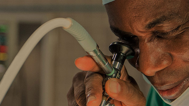 A surgeon carries out a procedure using an operating microscope