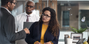 Image of three workers collaborating beside a desktop.