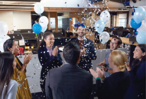 Microsoft employees celebrating an accomplishment in a gathering space in a Microsoft office.