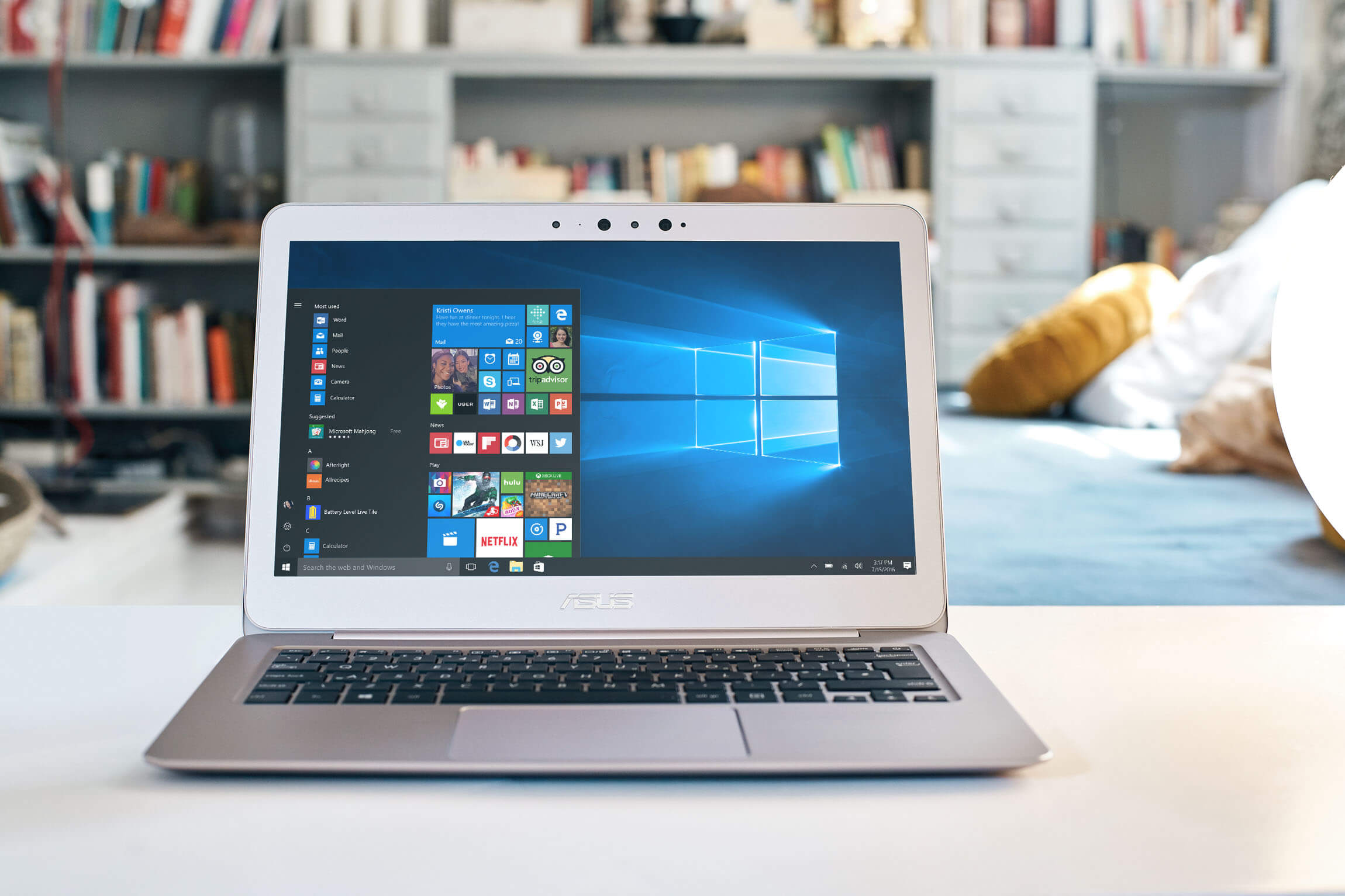 An open laptop sits on a low table in front of a bookshelf in a sitting room.