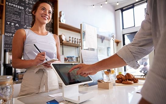 Customer using touch screen to make payment at a coffee shop