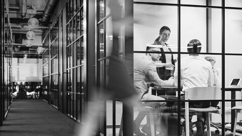 black and white photo of workers in a windowed conference room