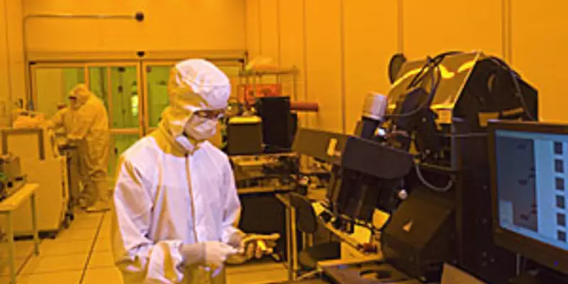 Man in a clean suit stands in front of a chip oven