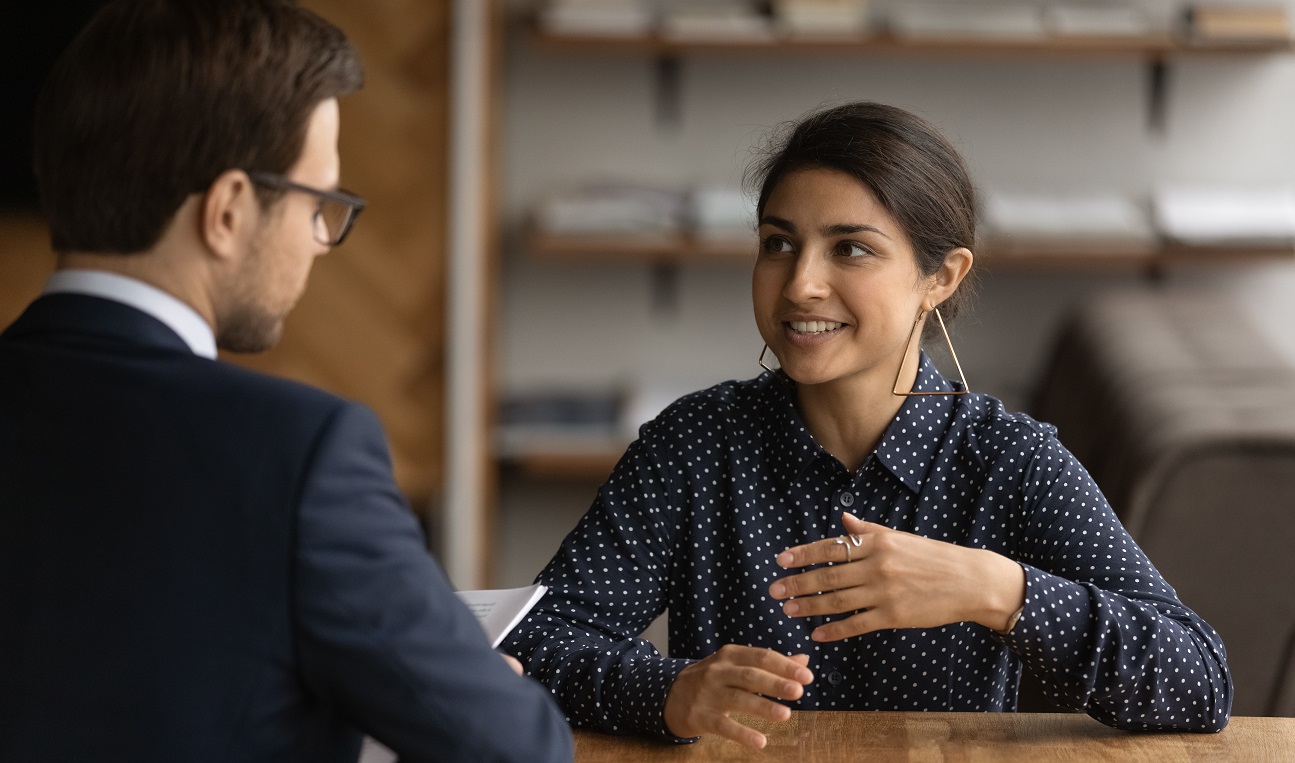 Confident young Indian woman have recruitment talk with male employer at office interview. Ethnic female job candidate speak with boss or recruiter at meeting. Employment, hiring concept.