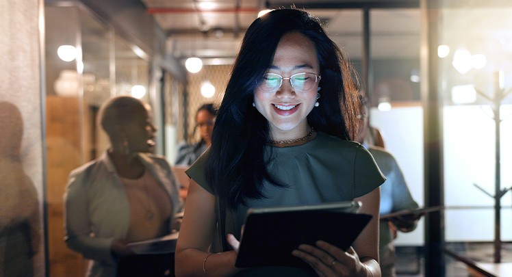 A woman holding a tablet in front of a group of people.