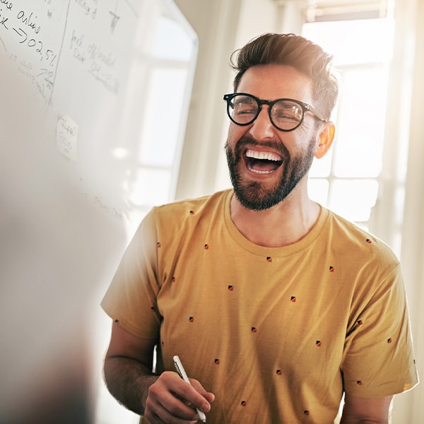 A person laughing in front of a whiteboard