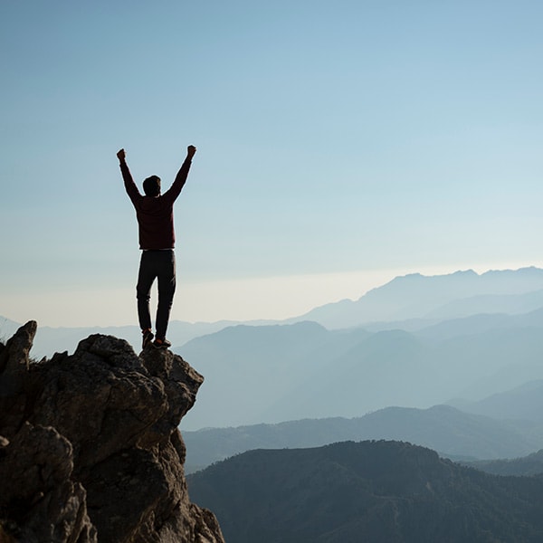 A man standing on top of a mountain with his arms raised.