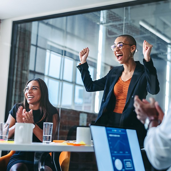 A group of business women clapping at a meeting.