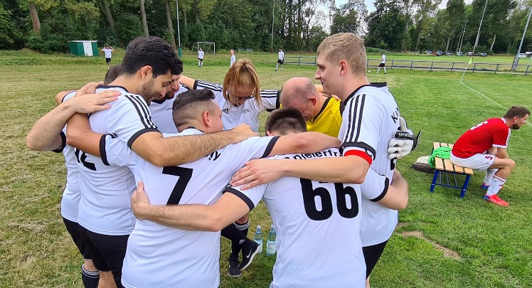 A group of soccer players huddle together on a field.