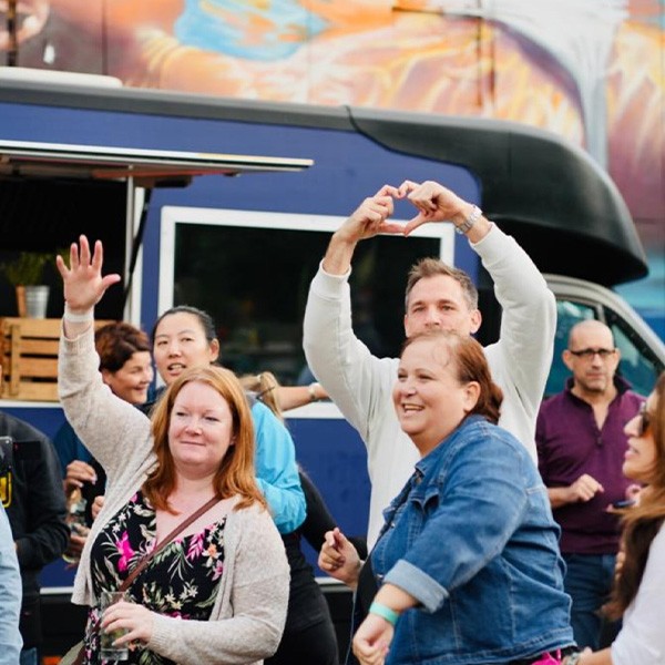 A group of people posing in front of a food truck.