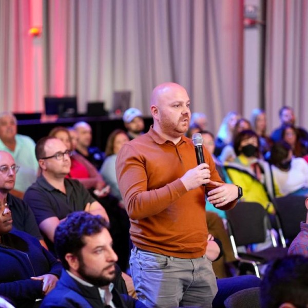 A man is speaking to an audience in front of a microphone.