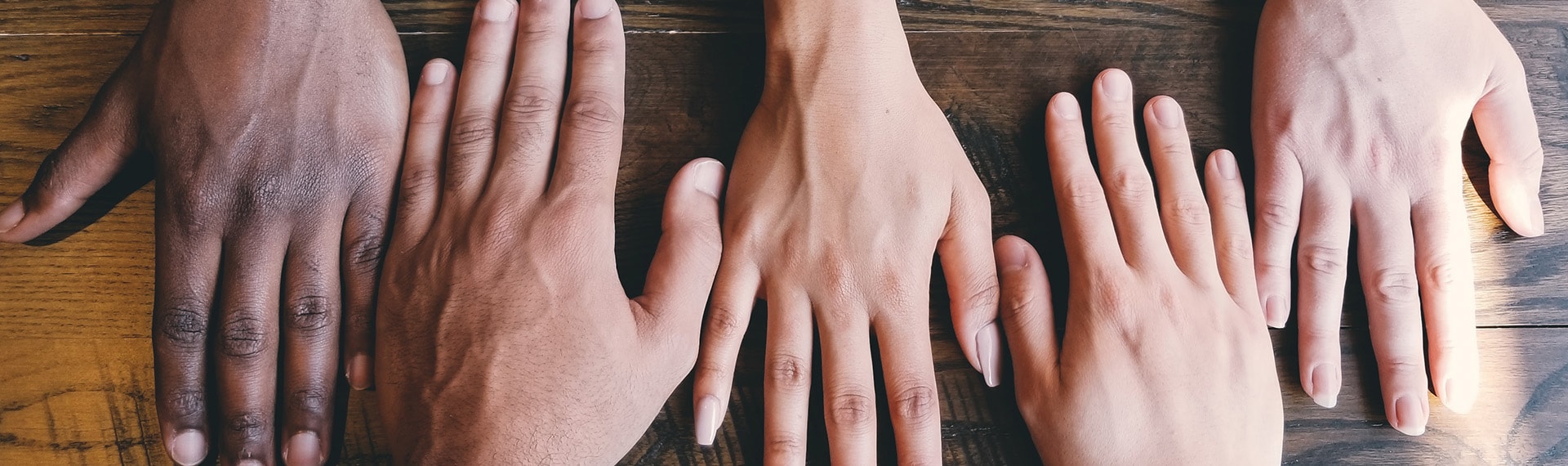 A group of people's hands on a wooden table.