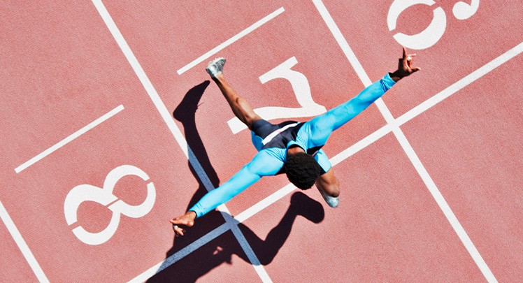 A man running on a track with his arms outstretched.