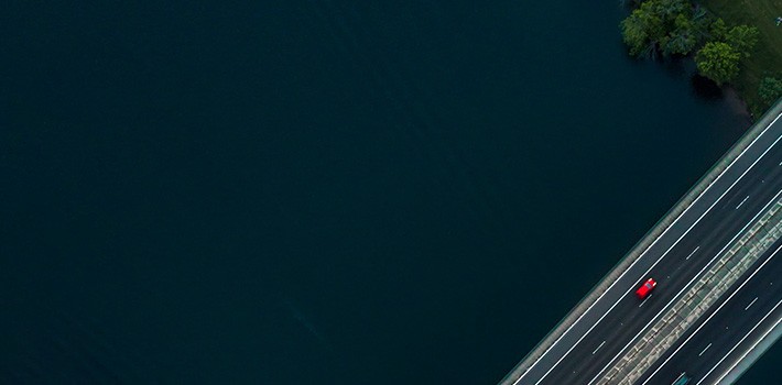 An aerial view of a highway with a car driving on it.