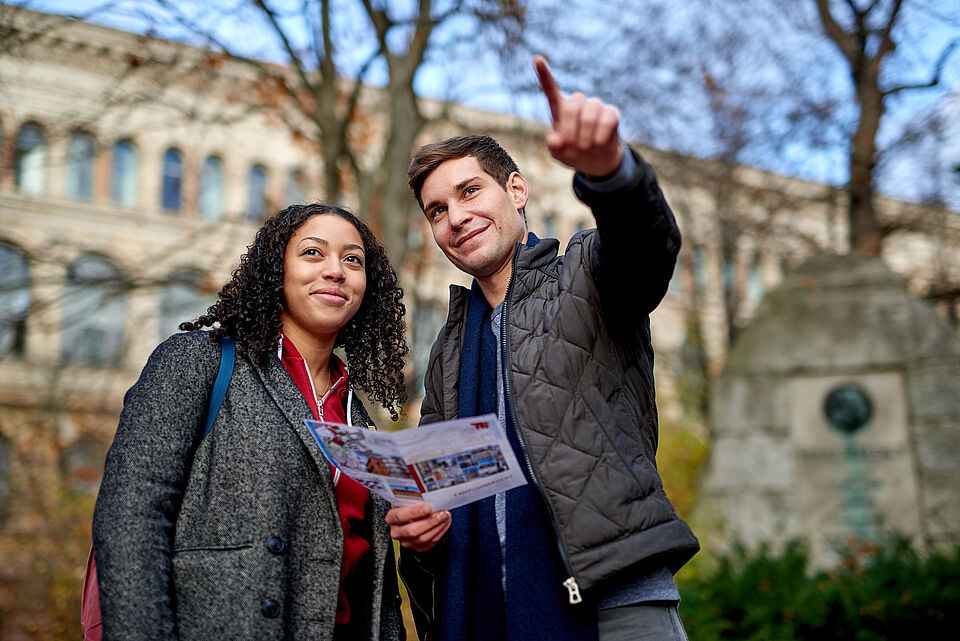 Studierende auf dem Campus der Technischen Universität Berlin mit einer Campuskarte in der Hand