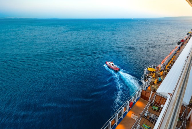 Boat leaving cruise ship on the ocean.